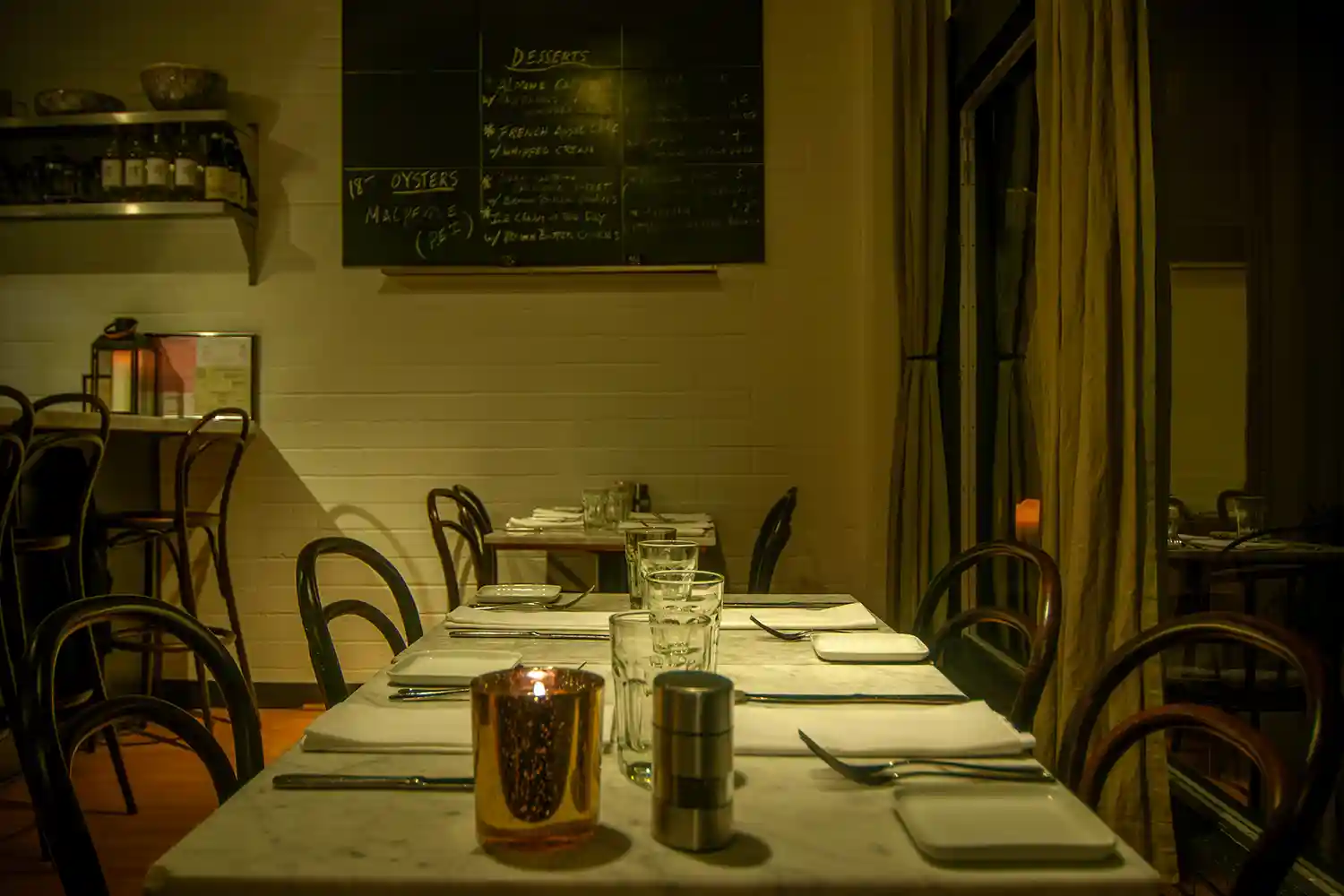 View of Bistro Elan's interior featuring marbled tables and soft lighting, offering a stylish yet relaxed atmosphere near bustling California Avenue.