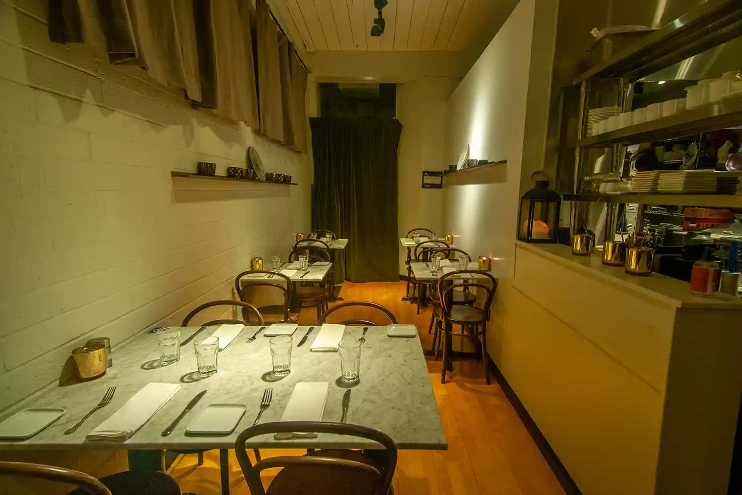 View of Bistro Elan's elegant interior featuring marble tables, wooden chairs, and soft lighting, creating a sophisticated and inviting atmosphere